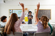 © Monkey Business - High School Students Raising Hands To Answer Question Set By Teacher In Classroom