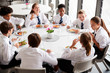 © Monkey Business - Group Of High School Students Wearing Uniform Sitting Around Table And Eating Lunch In Cafeteria