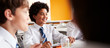 © Monkey Business - Group Of High School Students Wearing Uniform Sitting Around Table And Eating Lunch In Cafeteria