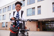 © Monkey Business - Portrait Of Female High School Student Wearing Uniform With Bicycle Outside School Buildings