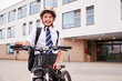 © Monkey Business - Portrait Of Female High School Student Wearing Uniform With Bicycle Outside School Buildings