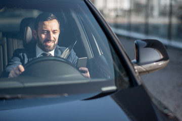 Happy businessman driving a luxury car, view from the outside through the windshield