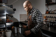 © horimono - Brutal young barista in an apron makes coffee at the bar in a modern cafe