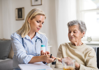 Wall Mural - A health visitor explaining a senior woman in wheelchair how to take pills.