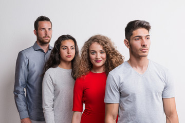 Wall Mural - Portrait of young group of friends standing one after another in a studio.