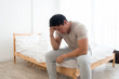© Asada - Asian man sitting on the bed and hand on forehead. Illness,stress,headache caused by overworking or hard work.