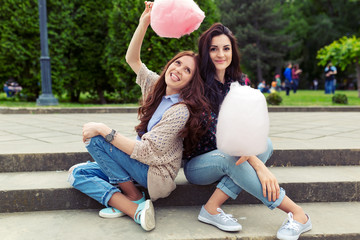 Wall Mural - Two cheerful girls having fun with cotton candy outdoor