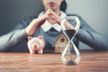 woman hand house model and piggy bank with clock