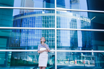 Wall Mural - Portrait of business woman with laptop in her hands standing next to the office building.