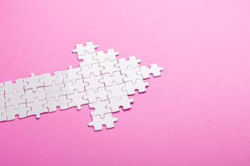 White puzzle. Arrow shape puzzle on pink background. Top view