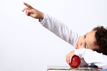 Wall Mural - Little boy with books and apple pointing his finger up