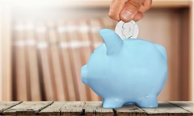 Wall Mural - Hand Putting a Coin in Piggy Bank