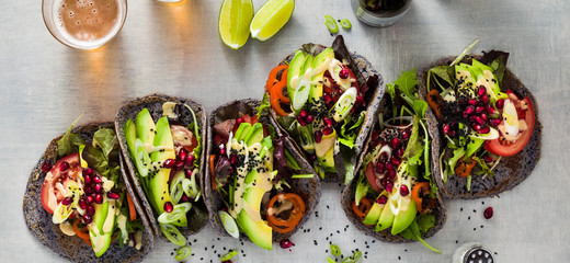 banner of Gluten-free vegan tacos from black bean  with tomato and avocado salad  with tahini sauce and pomegranate seeds. healthy fast food for the whole family or party and beer