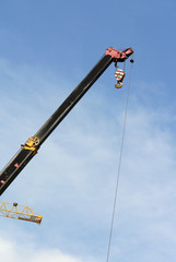 Wall Mural - Mobile crane boom with hooks and scale weight above blue sky. The boom used to lifting heavy load. 