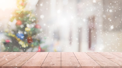 empty wood table top on blur with bokeh christmas tree background with snowfall - can be used for di