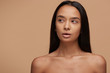 Portrait of a beautiful caucasian girl, looking aside, mouth slightly open, after spa or shower, with healthy clean fresh skin. Pretty woman with long black hair, naked shoulders over beige background