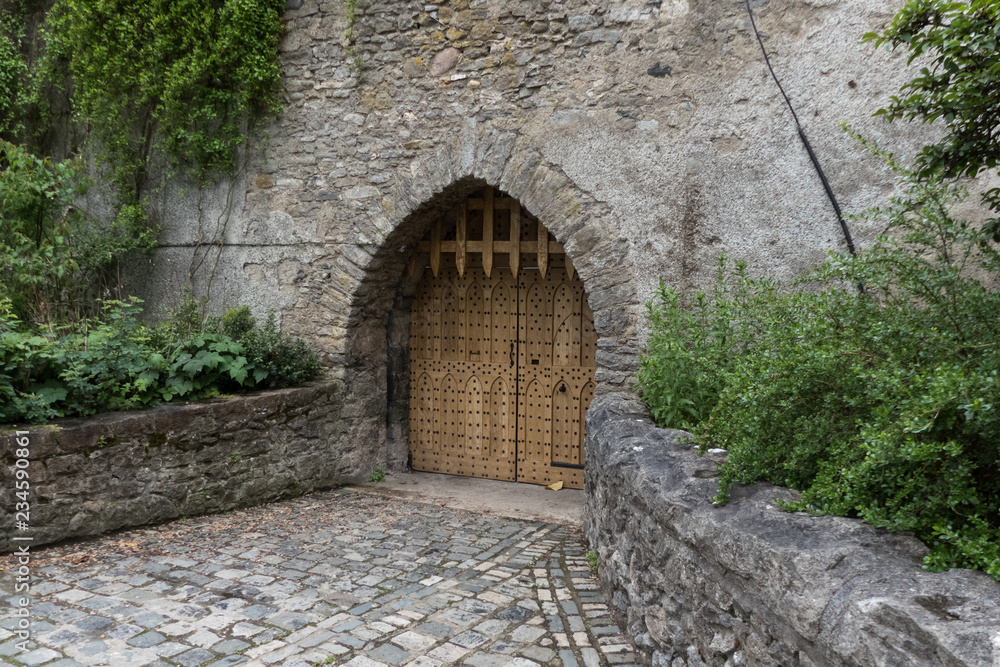 Heavy arched wooden door of a medieval stone castle set in the stone ...