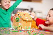 children having fun decorating the gingerbread house. the concept of family preparing to Christmas. selective focus