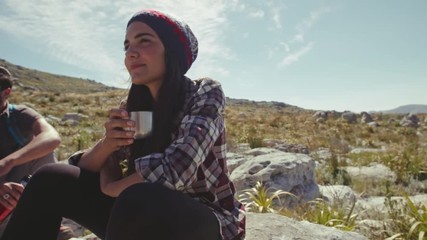 Wall Mural - Young woman drinking coffee and resting with friend during hike. Young people taking a break during hike.