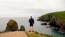 Man Standing On Cliff On A Breezy Day 4k
