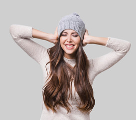 Wall Mural - Joyful woman winter portrait. Laughing girl wearing warm clothes studio shot. Isolated on gray background