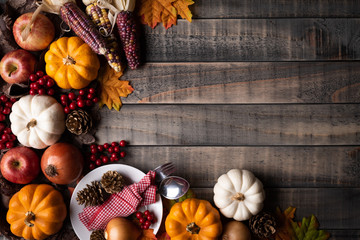 Wall Mural - top view of autumn maple leaves with pumpkin, apple, corn and red berries on old wooden background. 