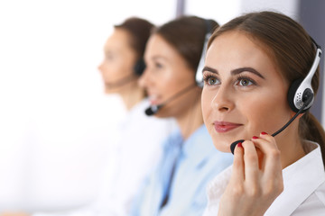 Call center. Group of operators at work. Focus at beautiful business woman in headset