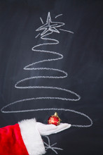 Santa Claus Hand Holding Christmas Ball. New Year And Christmas Greeting Card