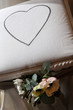 Cuore tenuto in mano da una sposaScatola bianca con cuore disegnato sopra e un fiore poggiato affianco