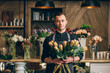 Man florist holding a protea flowers arrangements in modern interior floral shop. Small business, welcoming concept.