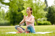 fitness, yoga and healthy lifestyle concept - happy woman meditating in summer park
