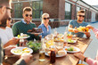 © Syda Productions - leisure and people concept - happy friends eating and drinking at barbecue party on rooftop in summer