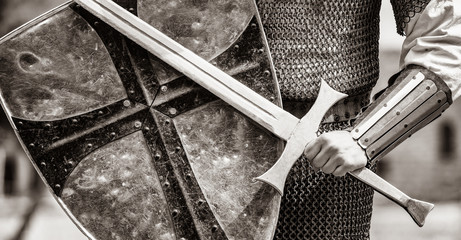 Canvas Print - Closeup view on traditional medieval knight with shield and sword. Image in black and white color style