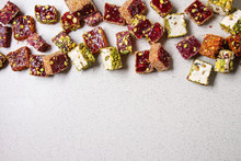 Variety Of Traditional Turkish Dessert Turkish Delight Different Taste And Colors With Rose Petals And Pistachio Nuts Over Grey Spotted Background. Flat Lay, Copy Copy Space