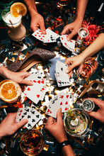 Cropped Shot Of Friends With Alcoholic Cocktails Playing Poker At Table Covered By Golden Confetti