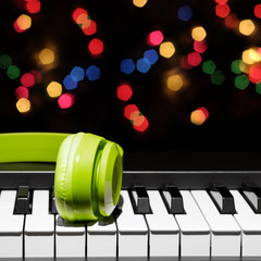 green headphone on piano keys, bokeh background