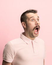 The Surprised And Astonished Young Man Screaming With Open Mouth Isolated On Pink Background. Concept Of Shock Face Emotion