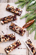 Baked shortbread sticks with chocolate, chopped nuts and dried cranberries glazed. .Millionaire's shortbread cookies and fir branches on vintage wooden table. Christmas baking
