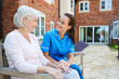 © Monkey Business - Senior Woman Sitting On Bench And Talking With Nurse In Retirement Home