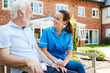 © Monkey Business - Senior Man Sitting On Bench And Talking With Nurse In Retirement Home