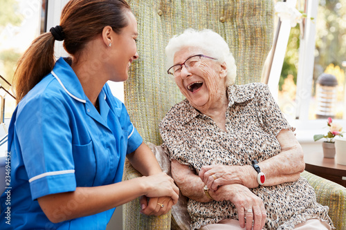 Fotomural Senior Woman Sitting In Chair And Laughing With Nurse In Retirement Home