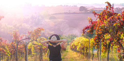 Girl in a hat at sunset. Nature Italy, hills and grape fields in the sunlight. Glare and sun rays in the frame. Free space for text. Copy space.