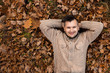 © Aliaksandr Marko - Autumn season, happiness and people concept - smiling young man lying on the ground or grass and fallen leaves in autumn park. Concept of autumn, autumn mood. Copy space.