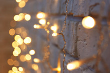 Selective Focus. Soft Yellow Christmas Lights With Bokeh Effect. Festive Blurry Texture Background With Many Lit Mini Lamps, New Year Holiday Decorations. Close Up, Copy Space.