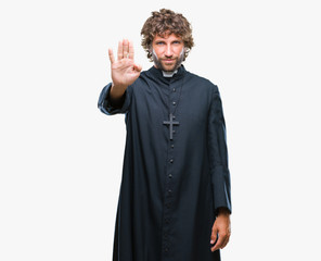 Canvas Print - Handsome hispanic catholic priest man over isolated background doing stop sing with palm of the hand. Warning expression with negative and serious gesture on the face.