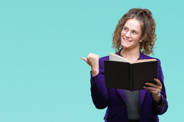 Sticker - Young brunette student girl wearing school uniform reading a book over isolated background pointing and showing with thumb up to the side with happy face smiling