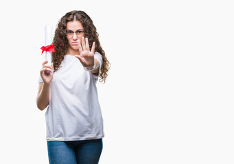 Poster - Young brunette girl holding degree and wearing glasses over isolated background with open hand doing stop sign with serious and confident expression, defense gesture