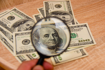 magnifying glass lies on american dollars on table