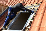 Fototapeta Do pokoju - DachdeckerDachdecker baut Dachfenster konzentriert auf dem Dach in rote Dachziegel Dächer ein