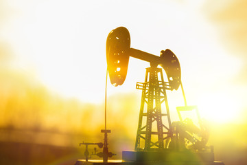 Wall Mural - silhouette of an oil drilling pump against a background of sun rays in the sunset